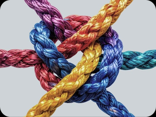 Bunte Seile, die zu einem Knoten verbunden sind, Symbol für die Zusammenführung mehrerer Kredite zu einem