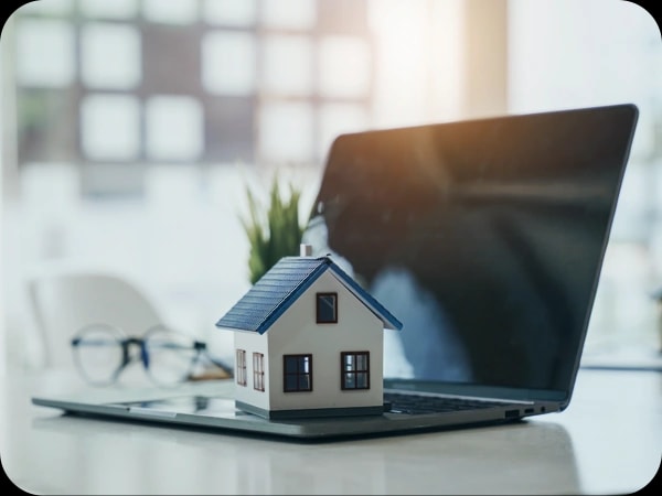 Casa en miniatura sobre un portátil, símbolo de la simulación de crédito online