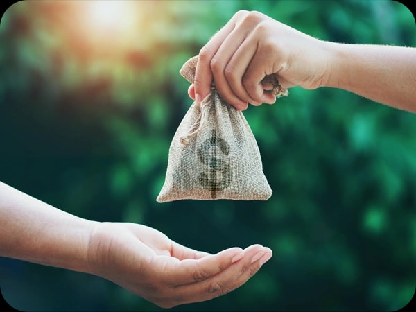 Mano entregando un saco de dinero, símbolo del financiamiento liberado por tramos